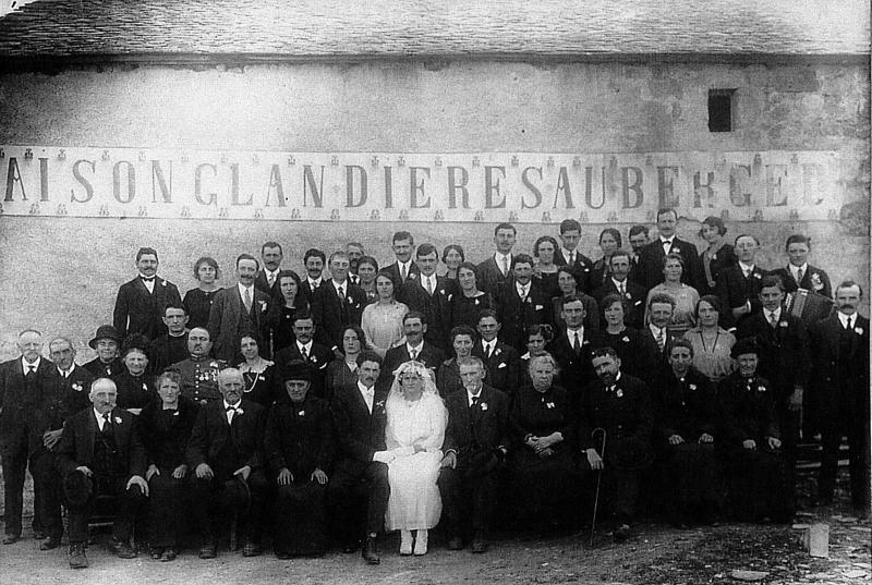 Mariage Capoulade-Entraygues avec accordéoniste (acordeonista) devant enseigne maison Glandières auberge (aubèrja), aux Bessades, 1924