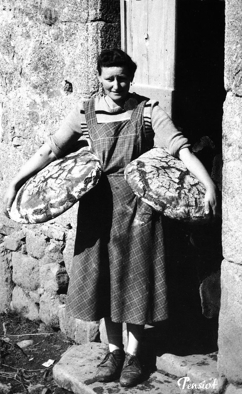 Femme portant deux miches (tortas) de pain sous les bras, en Viadène (secteur de Saint-Amans des Cots), mars 1957