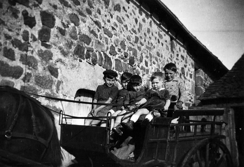  Cinq garçons sur un char à bancs attelé à un équidé devant une porte d'étable, à Recoules, 1944