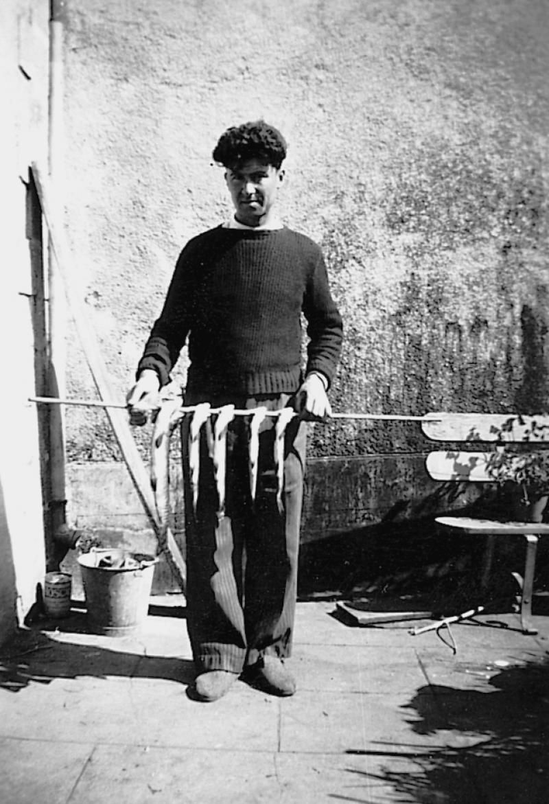 Homme montrant des prises de pêche : cinq truites (trochas) enfilées sur un bâton (baston), en Viadène (secteur de Sainte-Geneviève sur Argence)