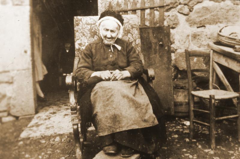 Vieille dame avec coiffe (còfa) assise dans un fauteuil