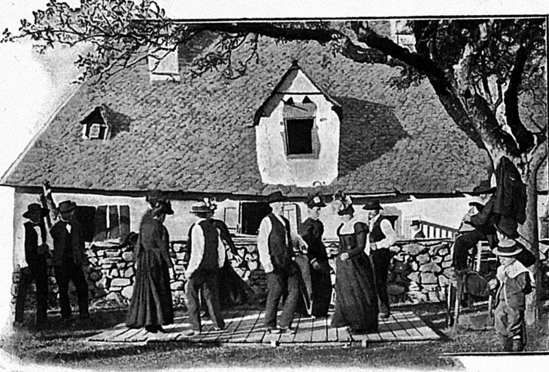 Danseurs de bourrée (dançaires de borrèia) et joueur de cabrette (cabretaire) devant maison (ostal), en Barrez, 1901