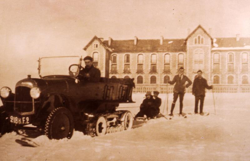  Traîneau (lisa) tracté par une autochenille et skieurs devant le sanatorium sous la neige (nèu), à Aubrac, 1924
