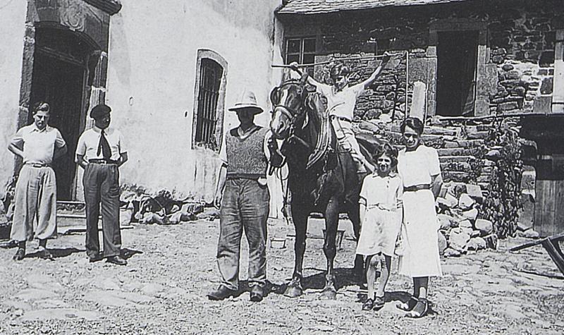 Famille et enfant juché sur un équidé dans cour de ferme, à Aulos, 1938