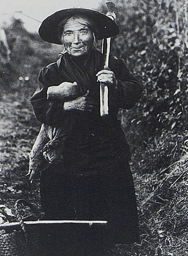 Femme naine avec houe sur l'épaule, à Bonnefon, vers 1910