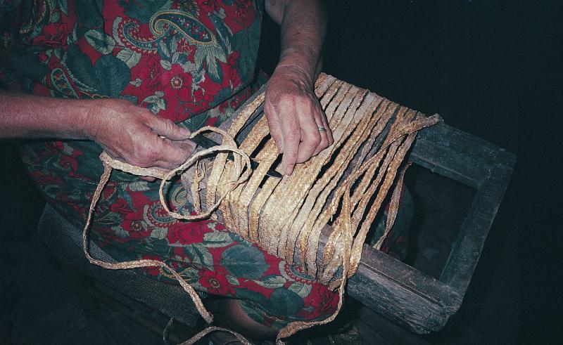 Femme confectionnant un cabas avec des tresses de paille de blé, à Trébosc, août 1993