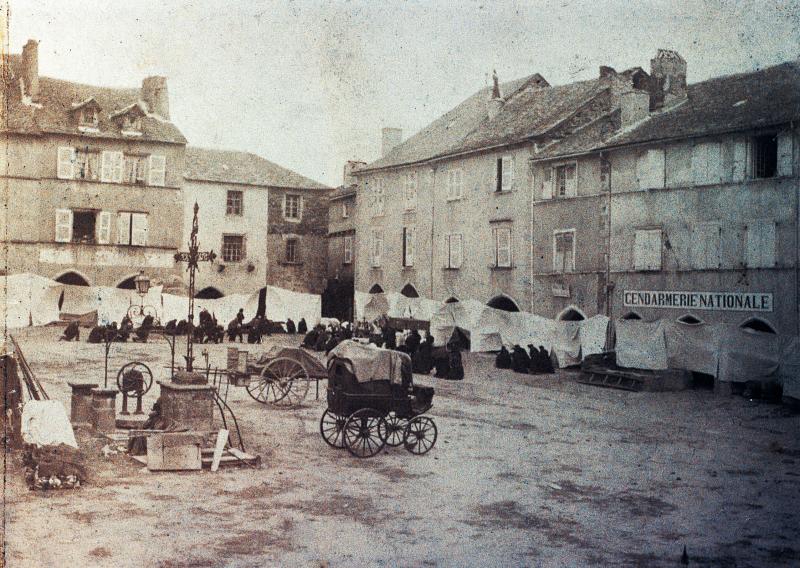 Chars (carris) et paroissiens (parroquians) agenouillés sur la place des arcades (gitats) pour une Fête-Dieu (Fèsta-Dius), 1895