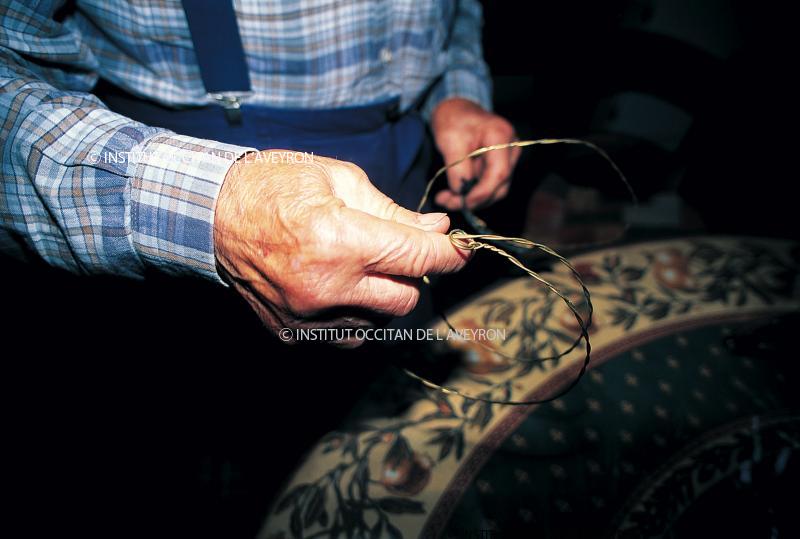 Homme montrant un collet (liçon, sedon) en fil de laiton, juillet 1995