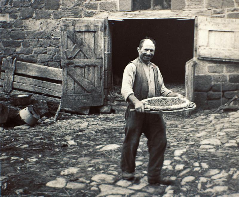 Homme devant une porte d'étable transportant une grande tarte (tarta) vers le four (forn) à pain, à Reiroles, 1959