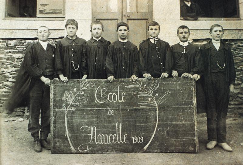 Sept écoliers (escolans) posant derrière un tableau noir, 1909