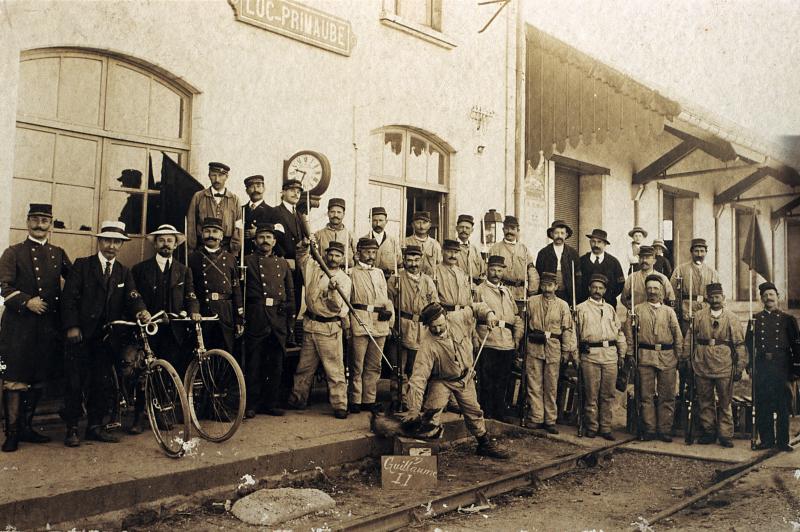 Autorités, soldats du 122e en uniforme avec fusils à baïonnette et blaireau (tais) sur le quai de la gare de Luc-Primaube, 1914