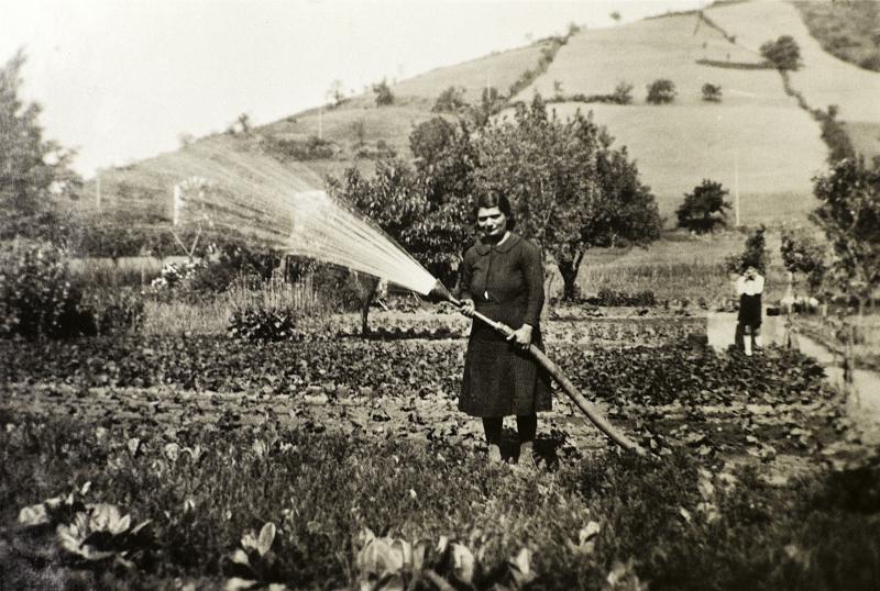 Femme arrosant un jardin (òrt) avec un tuyau équipé d'une paume, à La Salce, 1941