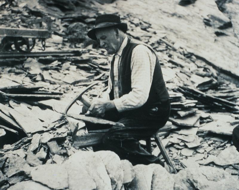 Homme taillant une lauze (lausa, tiula) de schiste dans une carrière (peirièira)
