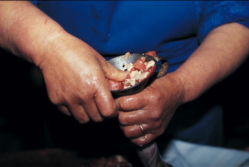Femme enfilant au moyen d'un entonnoir (embut) de la chair à saucisse (carn a salsissa) dans un boyau (budèl), mars 1995