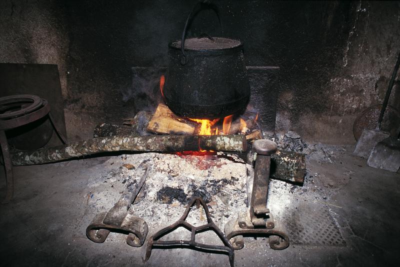 Trépieds (andèrs), chenets (capfoguièrs), feu (fuòc) allumé sous une marmite (ola) en fonte et pelles à feu (rispas), avril 1995
