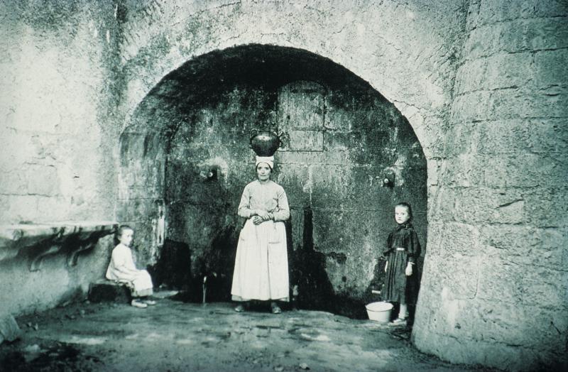 ​Deux enfants et une femme avec une cruche (cruga, dorca, dorna, pegal) sur la tête à la fontaine (fònt), à Saint-Antonin Nobleval (82)