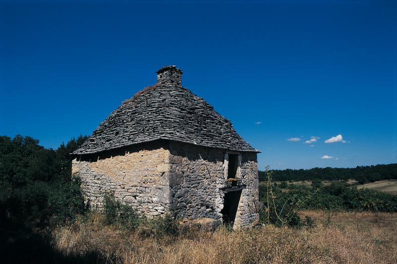 Cabane (cabana, cairon, casèla) en pierre sèche avec toiture (teulada) carrée à la base et circulaire au sommet et lanterne d'envol, au Mas de Bouyssou de Camboulan, août 1995