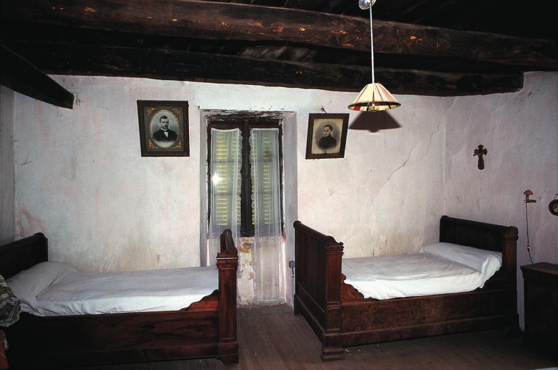  Deux lits (lièches) de coin, photographies des aïeux (aujòls, davancièrs) et crucifix (crotz) au mur, avril 1995