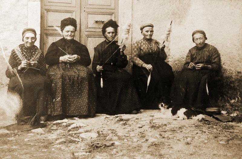 Trois femmes tricotant, deux femmes filant le chanvre (cambe, cambi) à la quenouille (conolha) et au fuseau (fuse), chien (can), à Cénac, vers 1910