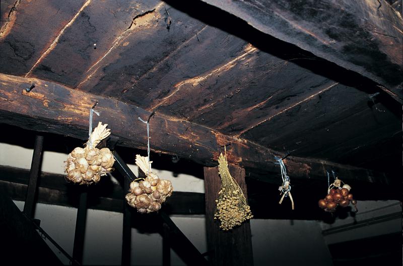 Paquets d'ail (alh), de camomille (camomilha) et d'oignons (cebas) suspendus à une poutre (fusta), aux Farguettes, mars 1995