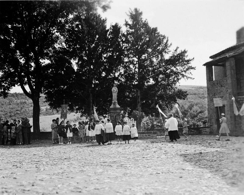 Bérets blancs, enfants de chœur (clergues) et curé (curat) à l'arrêt devant statue de la Vierge (Vièrja) pour un 15 août, années 1945
