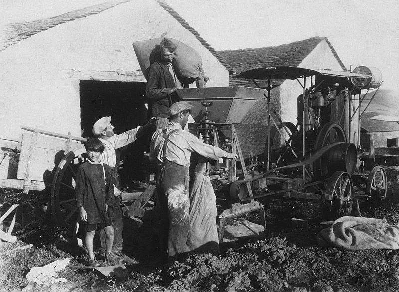 Hommes faisant de la farine (farina) avec un moulin (molin) ambulant et locomobile (caufusa) devant une grange (escura, fenial, granja), au Pradinas, vers 1935