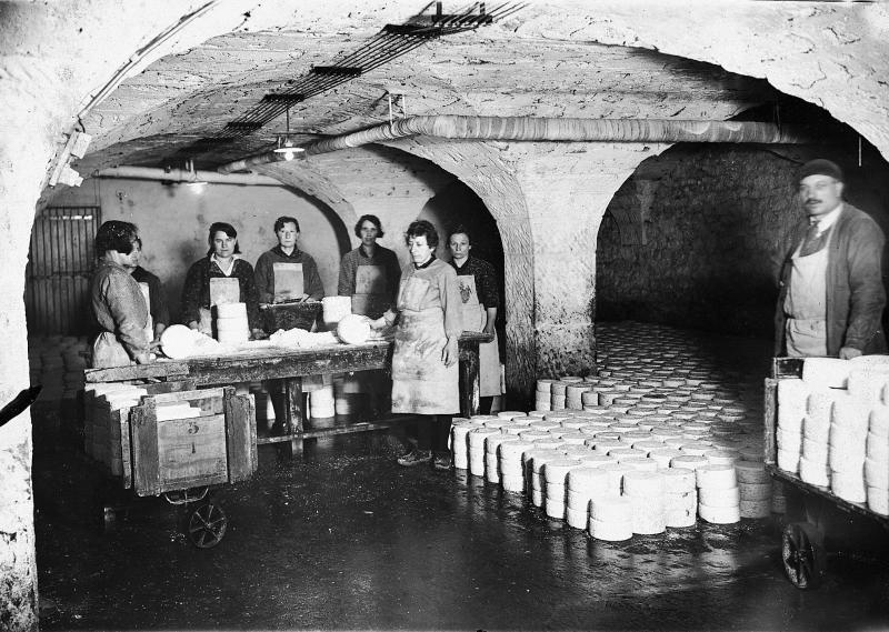  Sept cabanières (cabanièiras) et un employé de cave (òme de cava) salant les pains de roquefort dans une salle voûtée