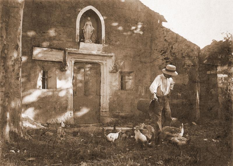 Homme donnant à manger à de la volaille (polalha) devant une chapelle (capèla), à l'Hermitage, 1930-1935
