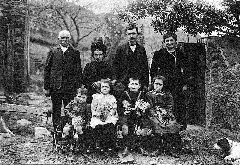 Enfants avec bouquets de fleurs, berger (pastre), forgeron (fabre, faure) et couturière (cordurièira) dans une cour de ferme (bòria), au Soulayrol, 1920