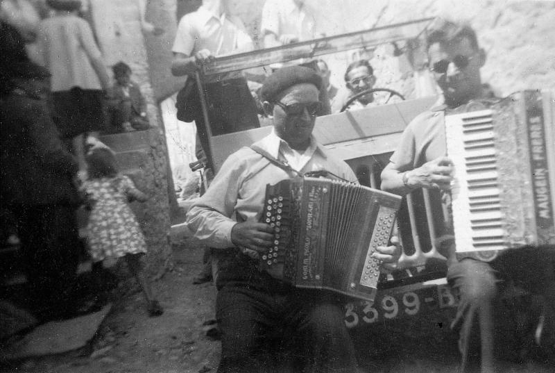 Deux accordéonistes (acordeonistas) jouant assis sur le parechoc d'une jeep durant le passage de la pomme (passar la poma), 1949