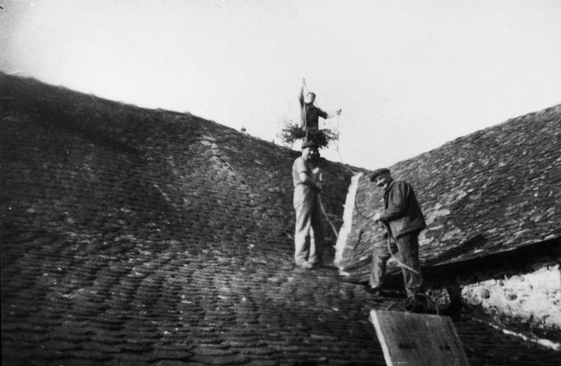 Trois hommes sur une toiture (teulada) ramonant une cheminée (chiminèia), au Puech