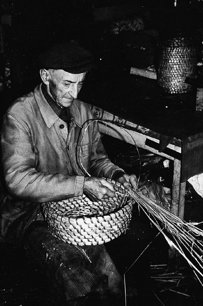 Homme confectionnant une vannerie en osier (vim) et en paille de seigle (segal), au Mas, vers 1975