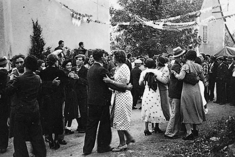 ​Couples dansant en plein air  devant deux musiciens (musicaires) et spectateurs un jour de fête (fèsta, vòta), à Marin, 1932