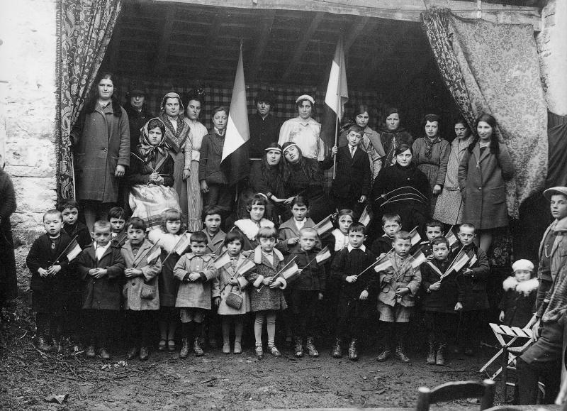 Enfants (dròlles, enfants) avec drapeaux et filles déguisées sur une estrade (empont) pour une séance récréative, 1926-1927