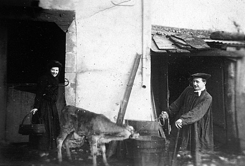 Femme avec panier (panièr) noir à la main et homme tirant avec un cordon (cordèl, liçon) un veau (vedèl), en Peyralés (secteur de La Salvetat Peyralès)