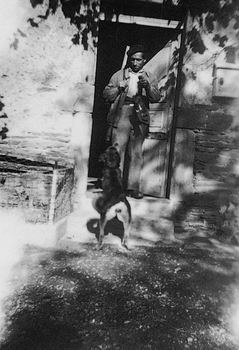 Chasseur (caçaire) montrant du gibier à un chien (can) sur le pas de porte de la maison (ostal), octobre 1952