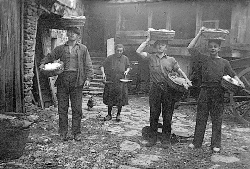 Trois hommes transportant sur la tête et sous les bras des corbeilles (palhassetas) de pâte à pain et femme avec deux poêles (padenas) contenant du farci (farç), à La Vialette de Frons, 1945