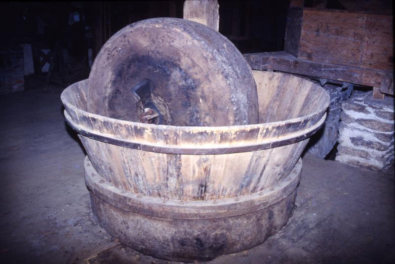 Moulin à meule verticale (ase, pilon, vertelh, vertuelh) pour écraser les cerneaux (nogalhs) de noix (nose, rascal, rascalon) avec maie (mag) cerclée de bois, au moulin hydraulique du Gô (anciennement