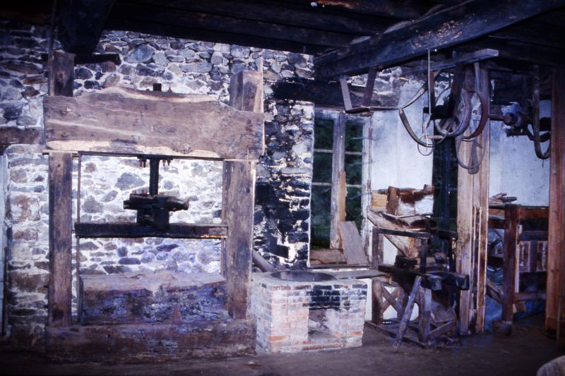 Pressoir (trèlh, truèlh) à vis métallique et foyer de chauffe pour la réalisation de l'huile de noix, au moulin hydraulique du Gô (anciennement moulin de Laval), juin 1992