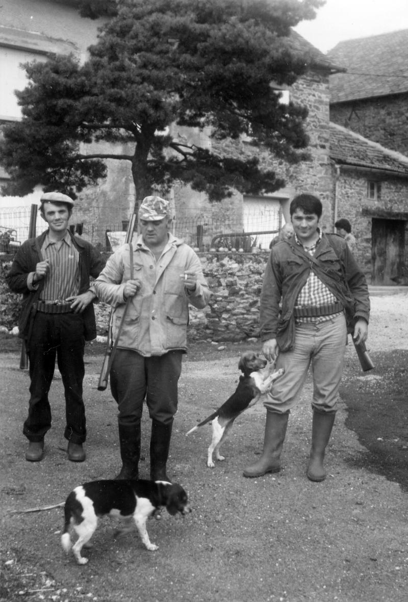 Trois chasseurs (caçaires) et deux chiens (cans) devant une maison (ostal)