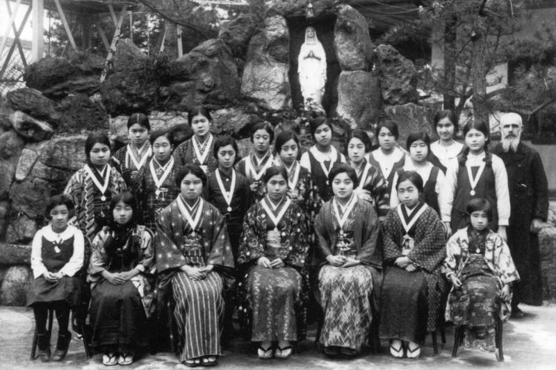 Missionaire (missionari) et jeunes filles en habits (vestit) traditionnels japonais devant une réplique de la grotte de Lourdes, au Japon, juillet 1930