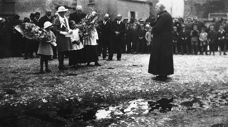 Fillette et enfants de chœur (clergues) avec gerbes de fleurs, femme lisant un discours de bienvenue à un curé (curat) devant des paroissiens (parroquians), 1933