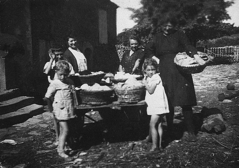 Enfants et femmes autour d'un charriot chargé de corbeilles (palhassetas) contenant de la pâte à pain, 1945