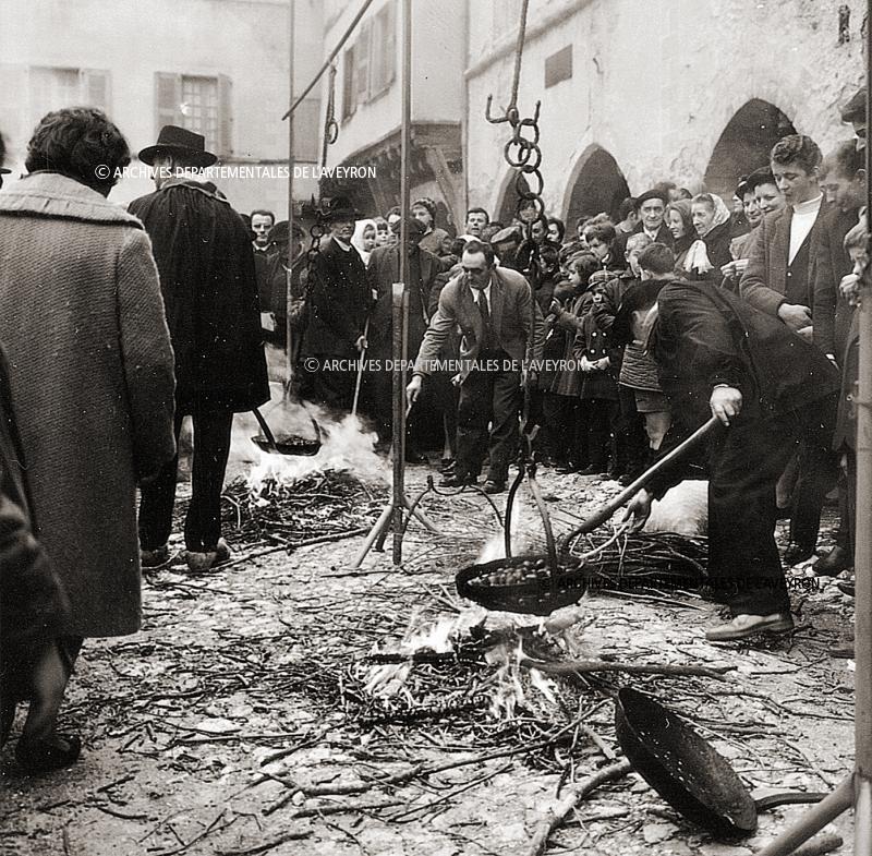Hommes faisant griller des châtaignes (castanhas) et villageois (vilatjors) sur la place des arcades (gitats) un jour de fête (fèsta, vòta)