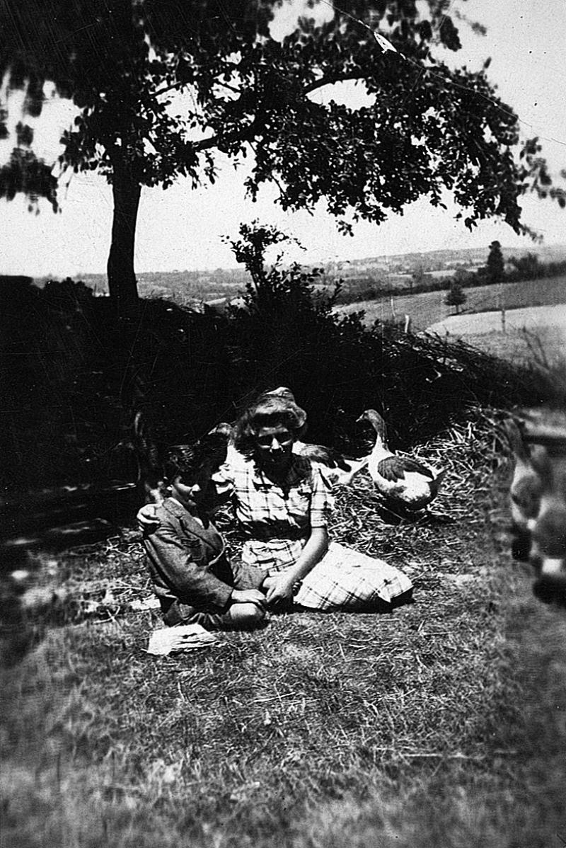 Deux enfants (dròlles, enfants) assis et oies (aucas), à Testet, 1940