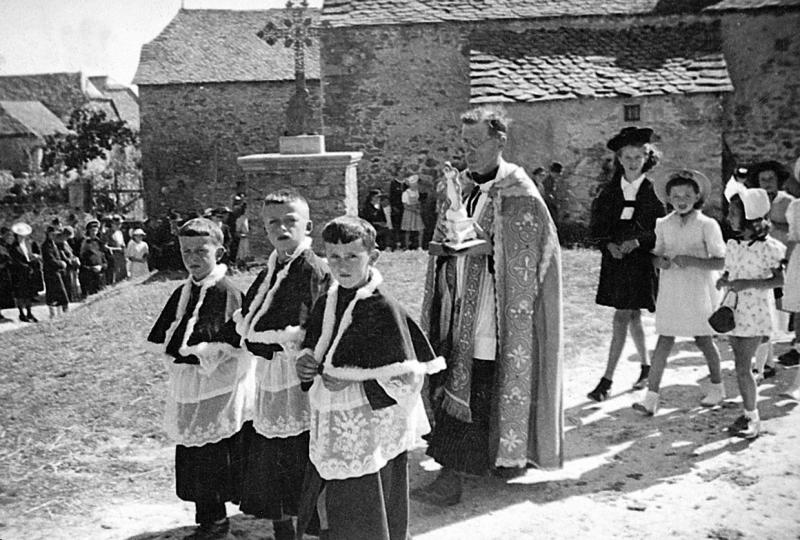 Enfant de chœur (clergues) en surplis, curé (curat), jeunes filles et paroissiens (parroquians) en procession, au Couderc, 15 août 1945