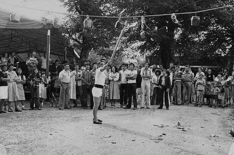 Homme aux yeux bandés cassant un pot en terre (topina) suspendu à une corde (còrda) un jour de fête (fèsta, vòta), au Théron, août 1970