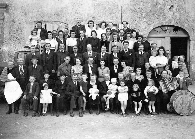 Famille réunie pour un baptême (batejalhas) avec deux serveuses (sirventas) et pièces montées en massepains (massapans), accordéoniste (acordeonista) et tambour (tambor), à Grillières, 1945
