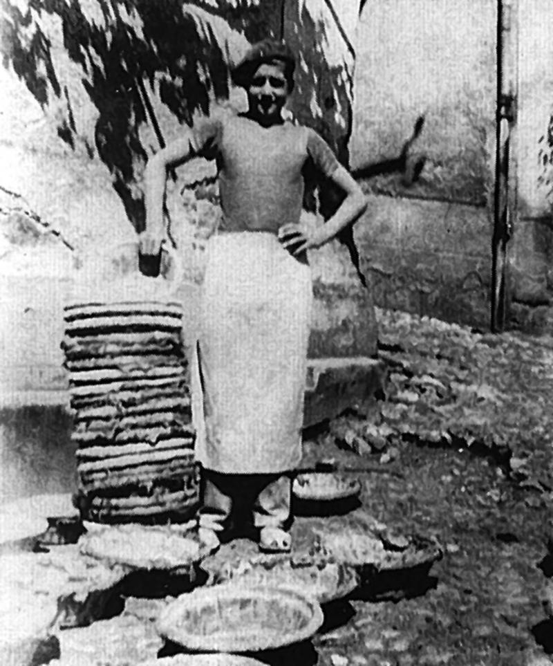 Jeune homme (jove, june òme) mettant à sécher les bannetons (palhassas pel pan) devant la boulangerie (bolanjariá), 1947