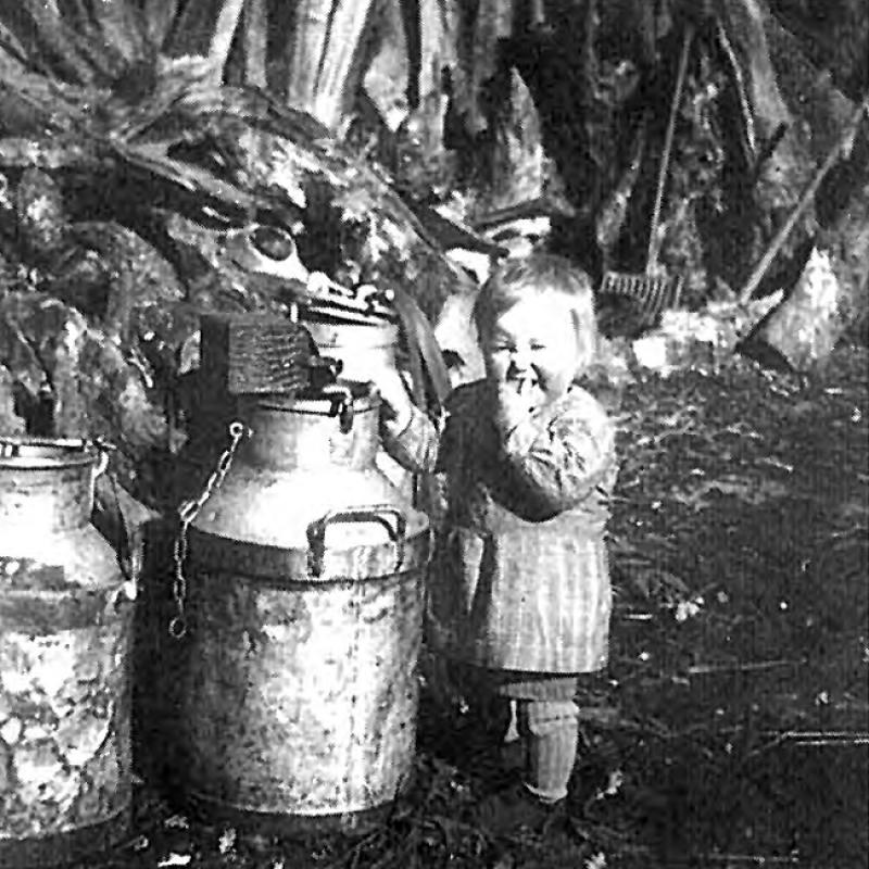 Enfant (dròlle, enfant) devant trois bidons de lait en fer blanc, en Ségala (secteur de Cassagnes Bégonhès), 1943